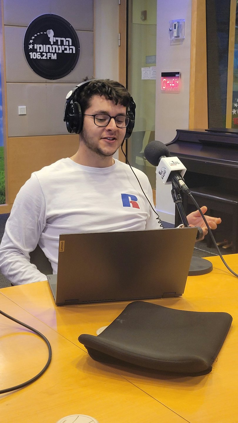 Hombre con gafas y auriculares habla a un micrófono de estudio.